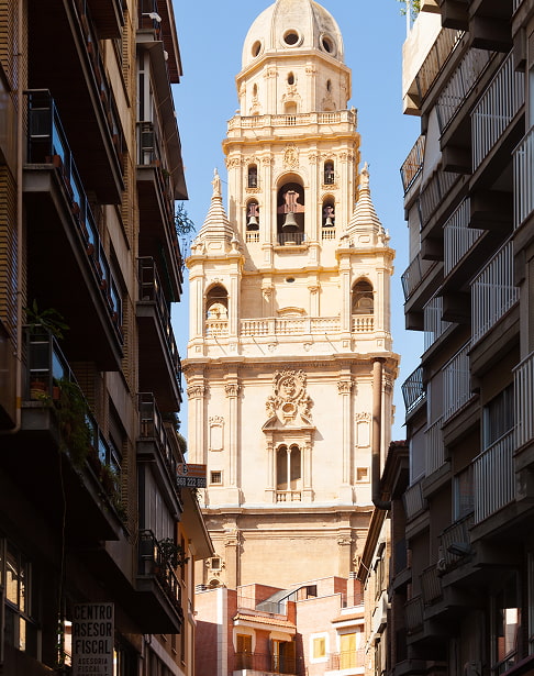 Torre de la Catedral de Murcia vista desde una calle del centro, entre edificios de viviendas
