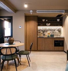Comedor amplio y despejado con mesa, sillas y cocinas al fondo en uno de los apartamentos turísticos en Murcia