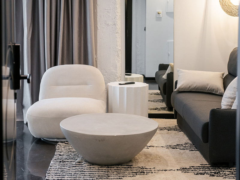 Apartamento Premium con balcón | Zona de estar Butaca blanca, mesa de centro de piedra y sofá gris sobre una alfombra en blanco y negro
