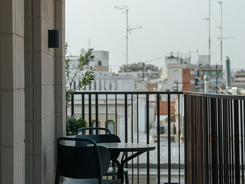 Apartamento Premium con balcón | Balcón Balcón con mesa y sillas negras y vistas a los tejados de la ciudad