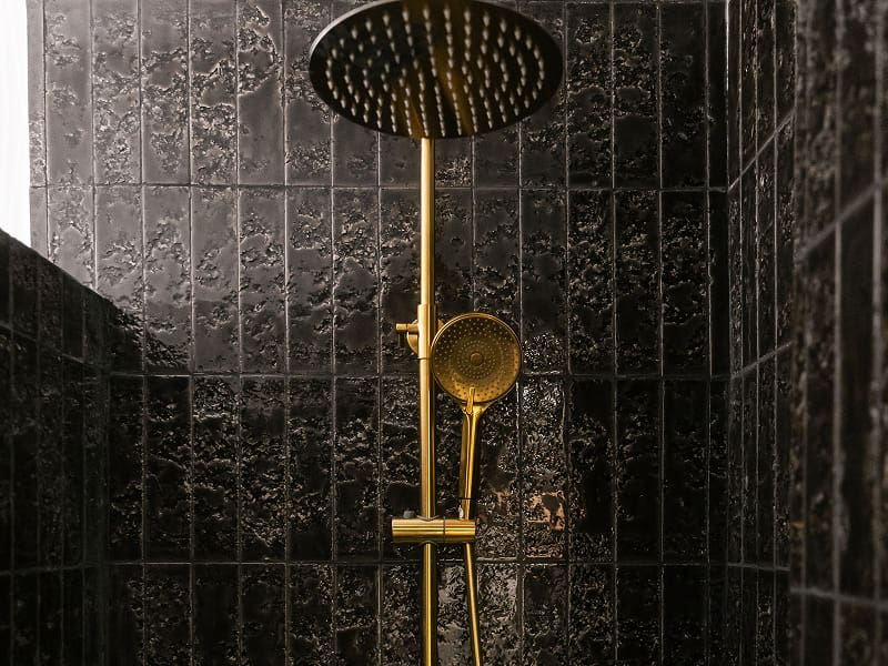 Apartamento Premium con balcón | Ducha Ducha con rociador efecto lluvia dorado y azulejos negros de textura irregular