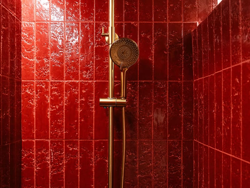 Apartamento Premium | Ducha Ducha con azulejos rojos brillantes y columna de ducha dorada