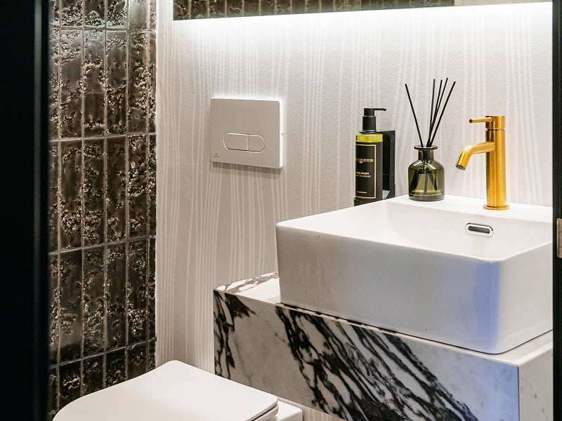Apartamento Premium | Baño Baño con lavabo sobre mueble de mármol veteado, azulejos oscuros e inodoro suspendido
