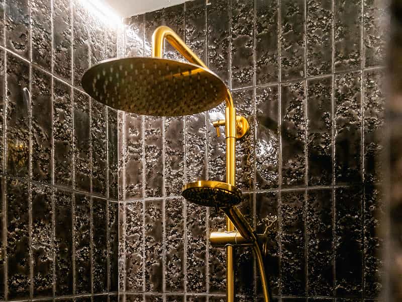 Apartamento para 2 | Ducha Rociador dorado de gran tamaño en una ducha de azulejos negros brillantes