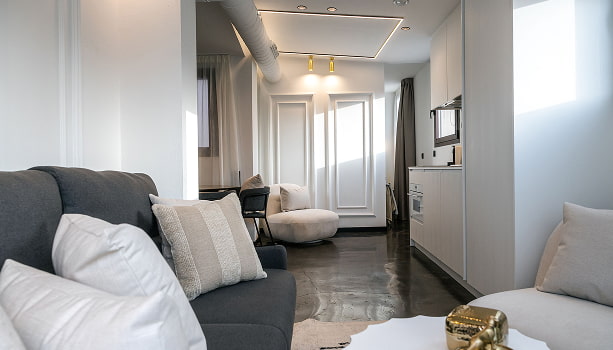 Ático con vistas | Salón Salón del ático con vistas de Los 36, con sofá gris, cojines blancos y figura dorada sobre la mesa