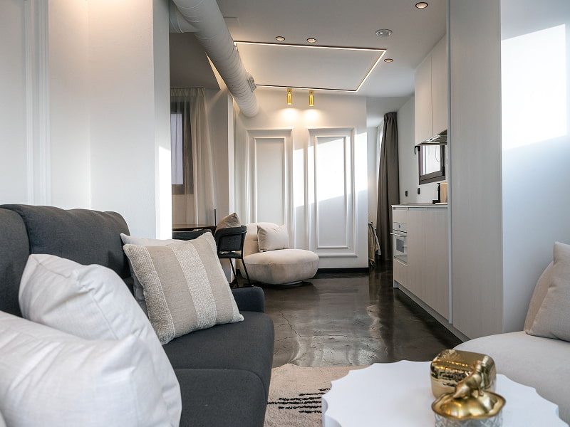 Ático con vistas | Salón Salón del ático con vistas de Los 36, con sofá gris, cojines blancos y figura dorada sobre la mesa