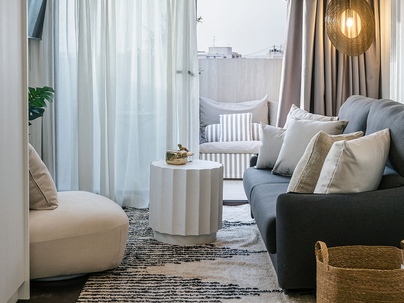 Ático con vistas | Zona de estar Zona de estar con sofá gris, butaca blanca, alfombra y lámpara de mimbre junto a la ventana