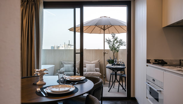 Ático con jacuzzi | Comedor y terraza Comedor con mesa redonda y cocina abierta, con salida a una terraza con sombrilla y olivo