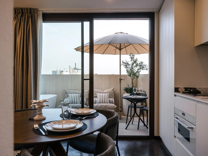 Ático con jacuzzi | Comedor y terraza Comedor con mesa redonda y cocina abierta, con salida a una terraza con sombrilla y olivo
