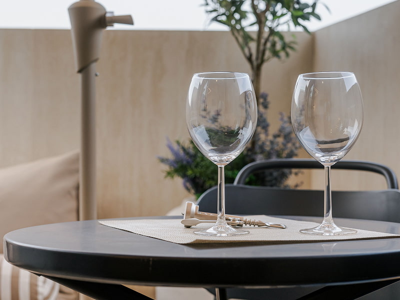 Ático con jacuzzi | Mesa en la terraza Mesa redonda con dos copas de vino y un plato junto a un olivo en la terraza