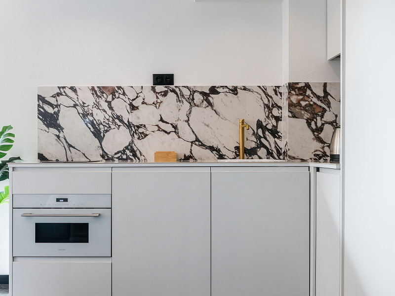 Estudio Premium con balcón | Cocina Cocina blanca con horno integrado y frente de mármol blanco con vetas oscuras