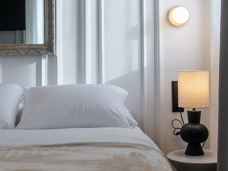 Estudio Premium con balcón | Mesilla Mesilla con lámpara de pantalla de lino y aplique de pared junto a almohadas blancas