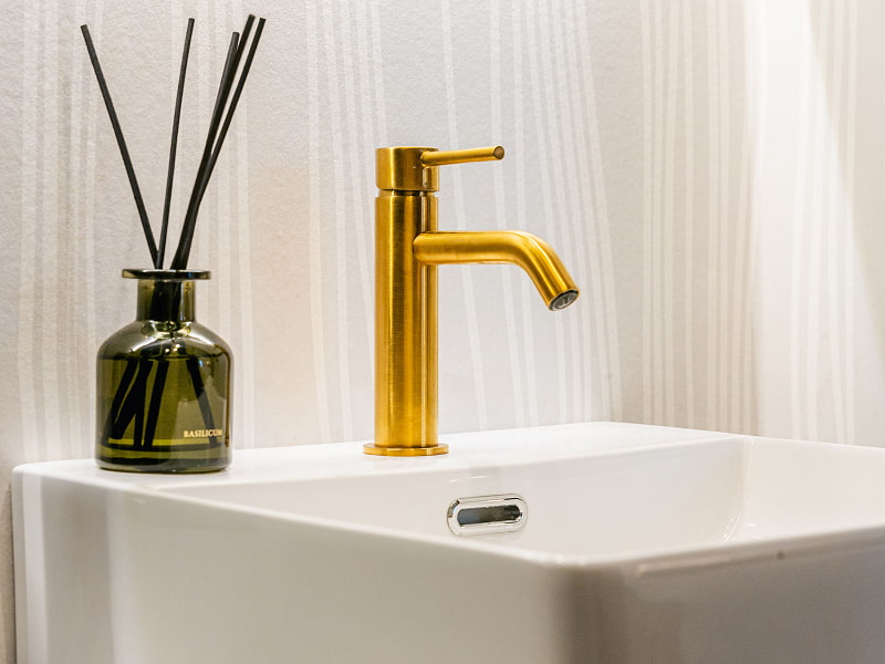 Estudio Premium con balcón | Baño Detalle del lavabo con grifo dorado y difusor de cristal verde