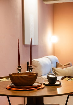 Decoración de estilo Marrakech Mesa con cuenco de madera y velas junto a paredes rosadas iluminadas con luz cálida