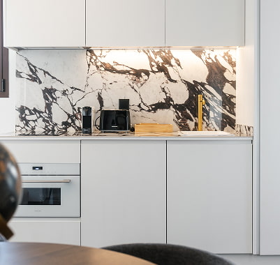Cocina completamente equipada Cocina blanca con horno, fregadero y frente de mármol veteado en un apartamento de Los 36