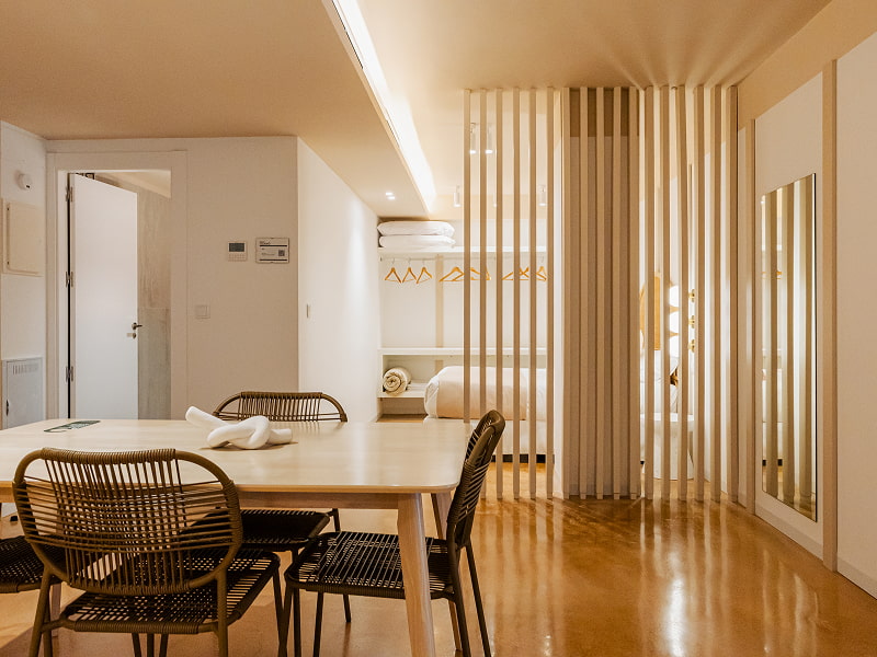 Apartamento 1 habitación | Comedor Mesa de comedor de madera con sillas de ratán junto a un separador de listones