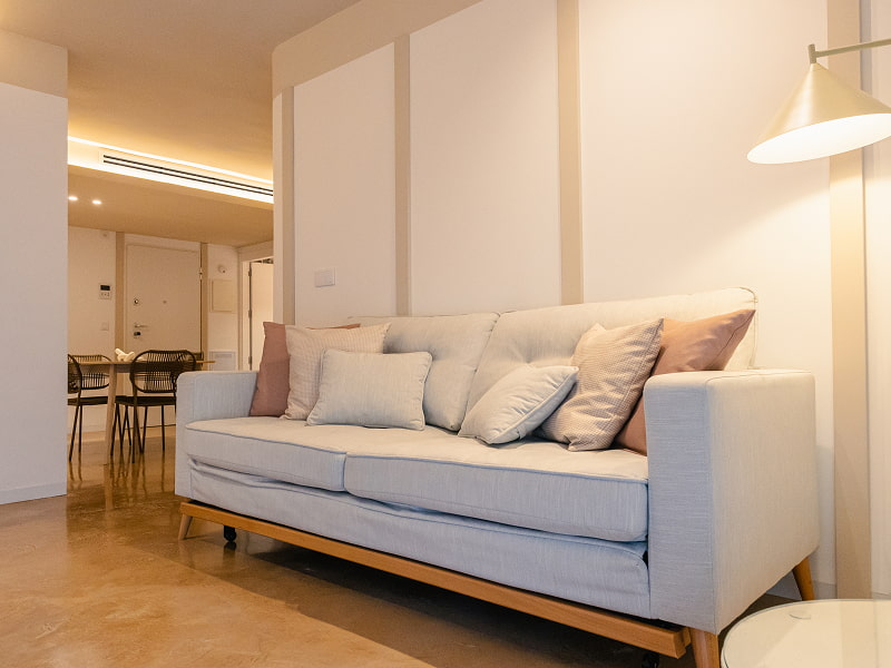 Apartamento 1 habitación | Salón Sofá azul claro con cojines rosas, lámpara de pie y comedor al fondo