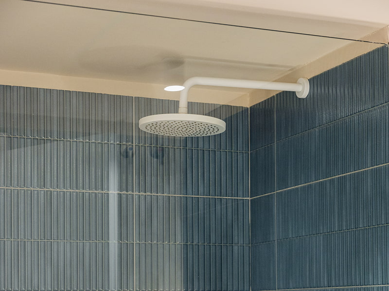 Apartamento 1 habitación | Ducha Ducha con rociador blanco, mampara de cristal y azulejos azules alargados