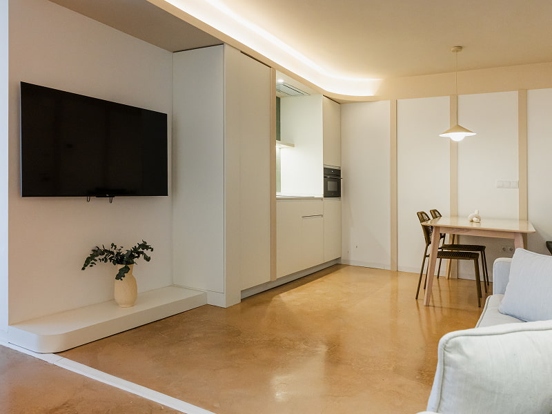 Apartamento 2 habitaciones | Salón y cocina Salón con televisión de pared y cocina integrada, con mesa de comedor al fondo