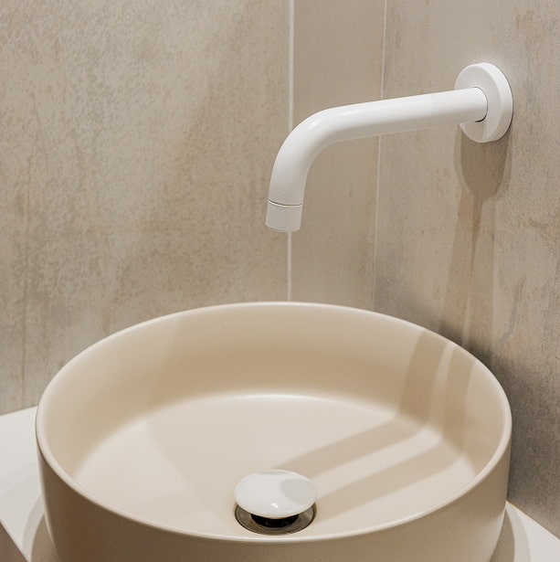 Lavabo de diseño Lavabo redondo sobre encimera, con grifo blanco de pared y fondo de piedra clara