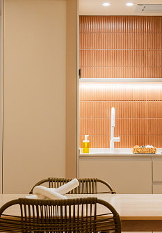Cocina y mesa de comedor Mesa de comedor con sillas de ratán frente a la cocina de azulejos terracota