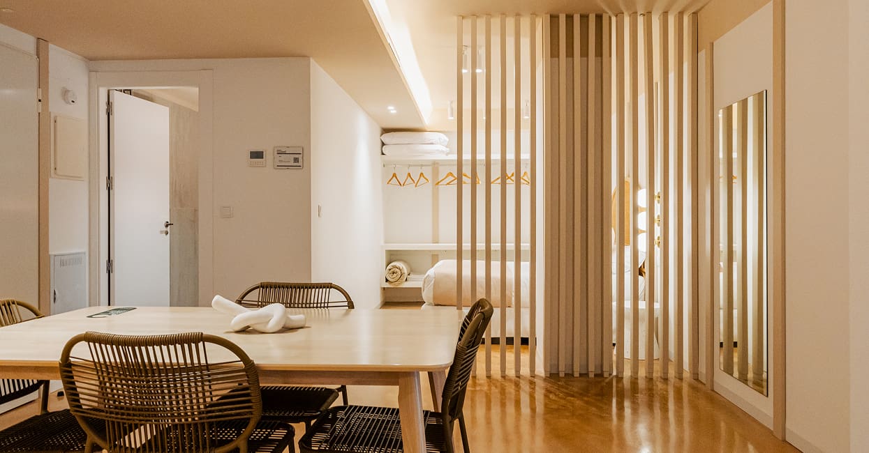 Comedor con separador de listones Comedor de Los 6 Murcia con mesa de madera y sillas de ratán junto a un separador de listones
