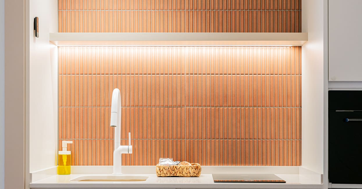 Cocina con frente de azulejos Detalle de la cocina con grifo blanco y azulejos terracota iluminados