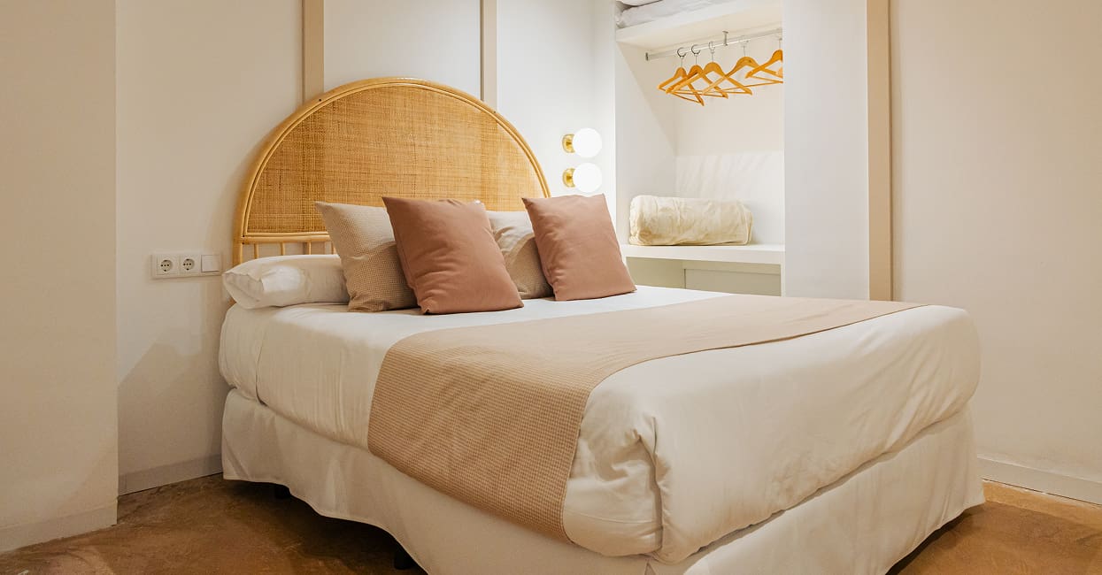 Dormitorio luminoso Cama con cabecero de ratán, cojines rosas y lámpara de techo dorada en un dormitorio de Los 6